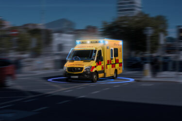 A yellow ambulance with blue lights going at high speed on the s